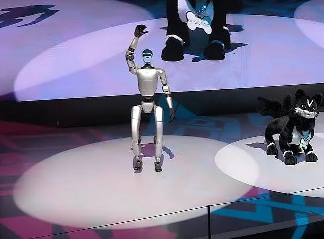Robot waving on a lit stage next to mascot characters during a brand activation