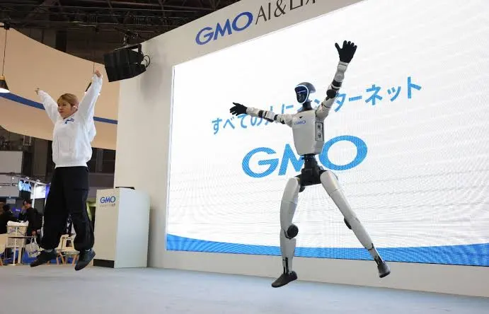 Humanoid robot and a performer jumping together in front of a large LED screen