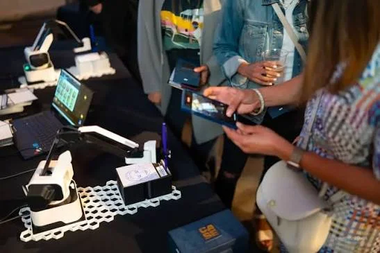 Guests scanning and photographing their portraits with phones beside SketchBot stations