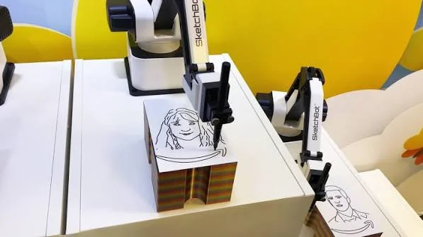 Close-up of a robotic arm drawing a line portrait on a sheet